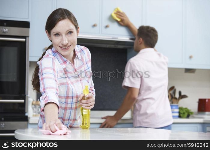Couple Cleaning Kitchen Surfaces And Cupboards Together