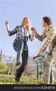 Couple climbing over wire fence outdoors