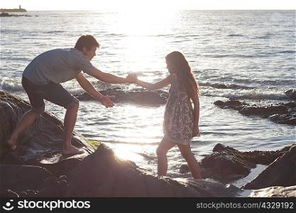 Couple climbing rocks on beach
