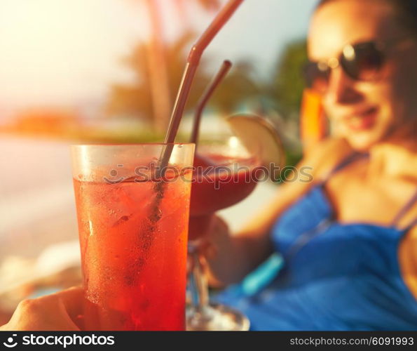 Couple clinking glasses with cocktails at poolside