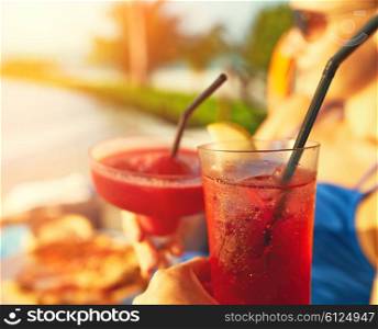 Couple clinking glasses with cocktails at poolside
