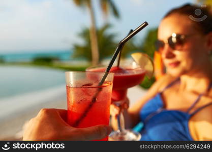 Couple clinking glasses with cocktails at poolside