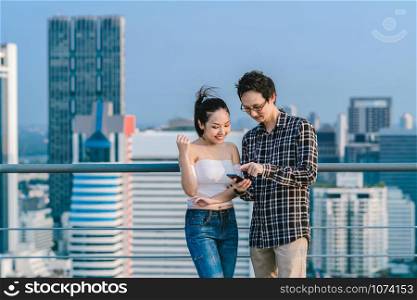 Couple colleague businessman and woman in casual suit are using smart mobile phone their business on the rooftop of downtown building in business center, achievement concept