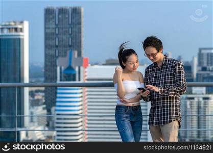 Couple colleague businessman and woman in casual suit are using smart mobile phone their business on the rooftop of downtown building in business center, achievement concept