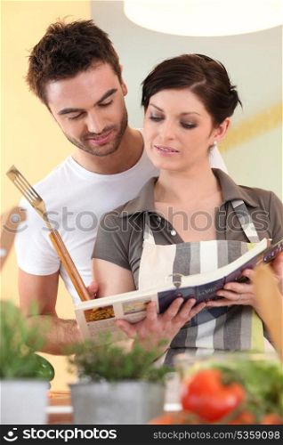 Couple cooking from recipe book