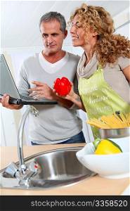 Couple cooking in kitchen with laptop computer
