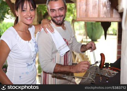 Couple cooking sausages on the barbecue