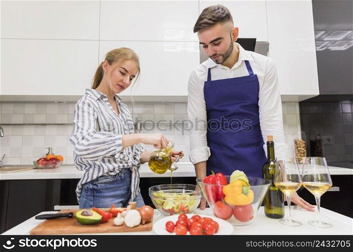 couple cooking vegetable salad with olive oil