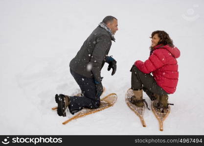 Couple crouching in the snow wearing snowshoes