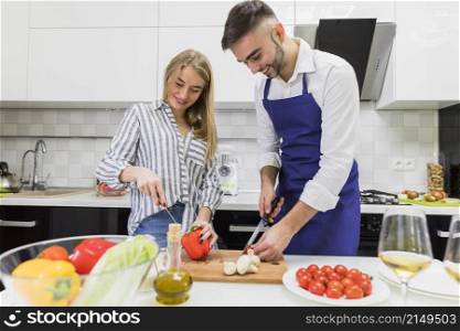 couple cutting vegetables wooden board