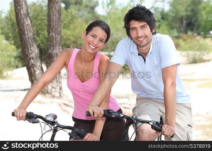 Couple cycling through a forest