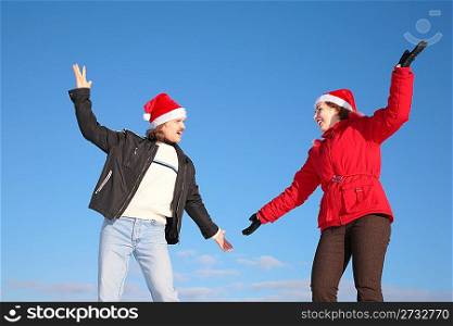 couple dance in santa claus hats against blue sky
