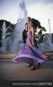 Couple dancing by fountain in plaza, sunset