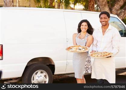 Couple Delivering Pizza Standing In Front Of Van