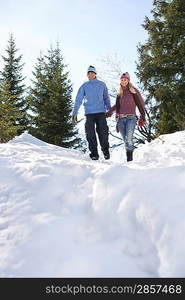 Couple descending snow-covered hill low angle view