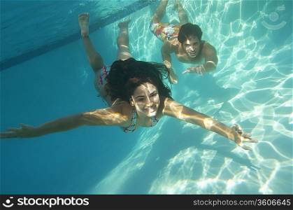 Couple diving in pool, underwater view