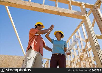 Couple doing &acute;hi 5&acute; in construction site