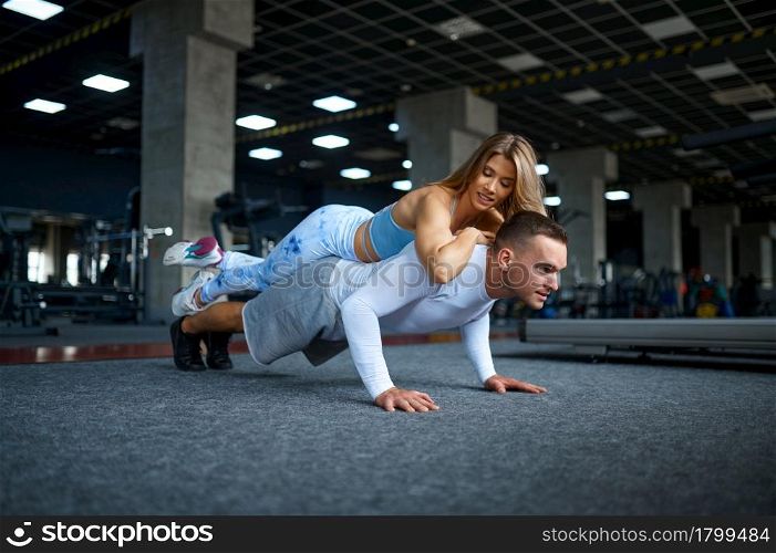 Couple doing push-ups, fitness training in gym. Athletic man and woman on workout in sport club, active healthy lifestyle, physical wellness. Couple doing push-ups, fitness training in gym