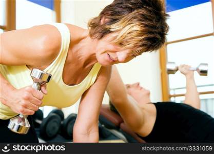 Couple doing their training with dumbbells in the gym