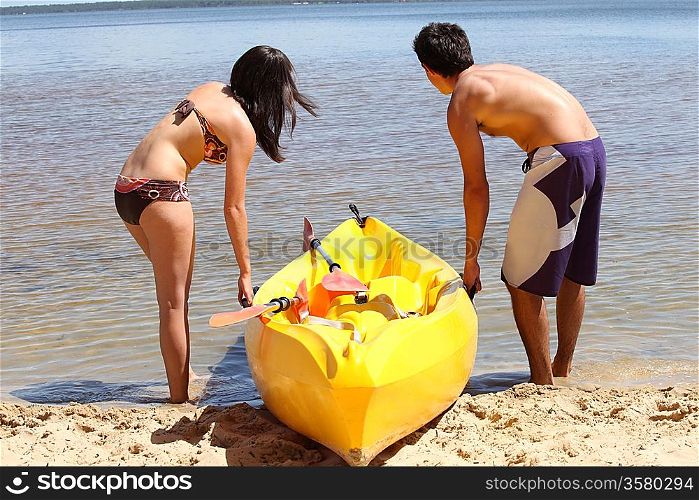 Couple dragging kayak onto lake