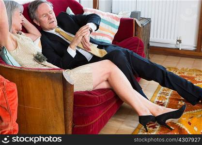 Couple dressed up, sitting on sofa and checking the time