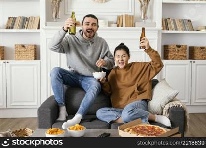 couple drinking beer eating snacks indoors