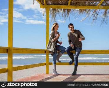 Couple Drinking Beer Together in empty beach bar during autumn time. young couple drinking beer together at the beach