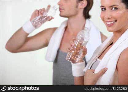 Couple drinking bottles water in the gym
