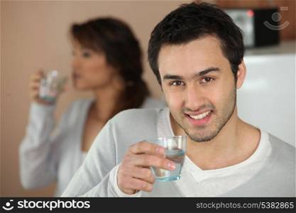 Couple drinking glasses of water at home