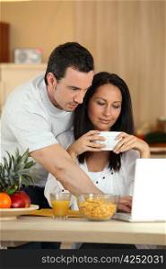 Couple eating breakfast in front of laptop