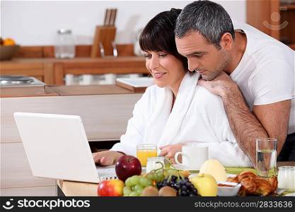 Couple eating breakfast together whilst browsing the internet