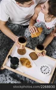 couple eating croissants with coffee bed