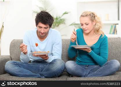 Couple eating diner on a sofa