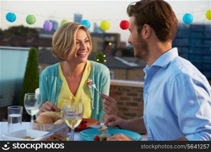 Couple Eating Evening Meal On Rooftop Terrace