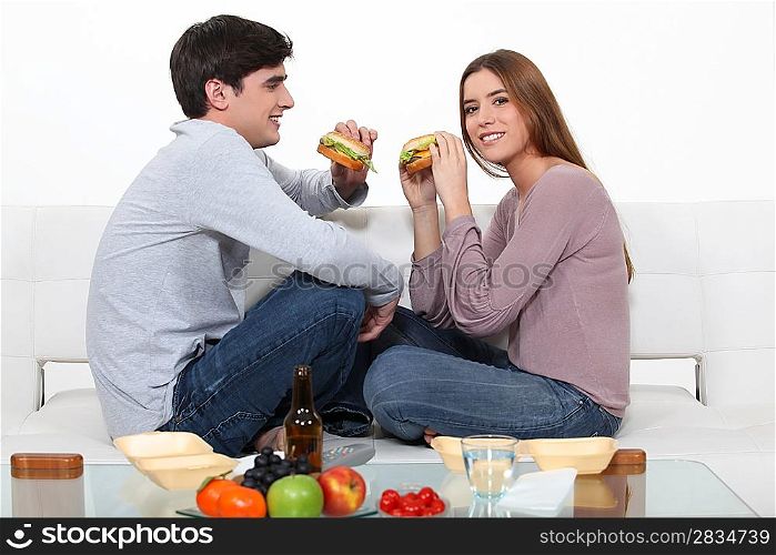 couple eating hamburgers on the couch