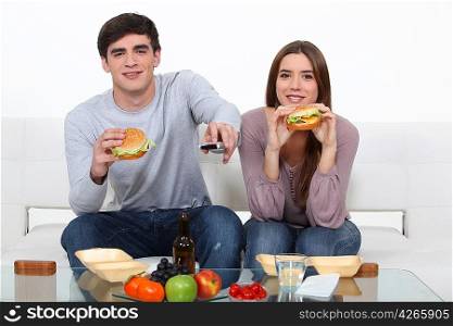 Couple eating junk food and watching television
