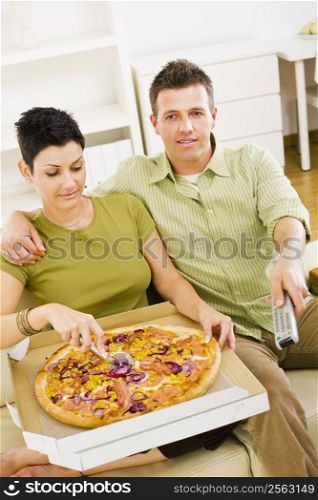 Couple eating pizza and watching TV at home.
