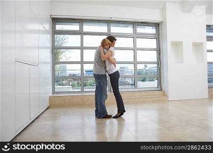 Couple embracing in empty apartment