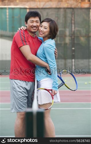 Couple embracing next to the tennis net
