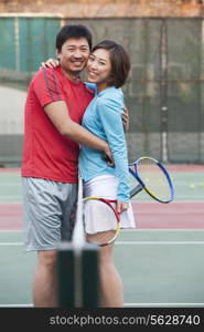 Couple embracing next to the tennis net