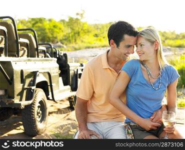 Couple embracing outdoors looking in eyes jeep in background