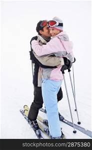 Couple embracing standing on skis on ski slope