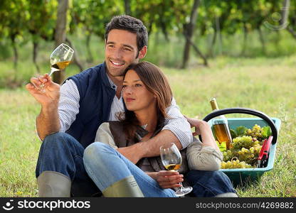 Couple enjoying a bottle of wine whilst harvesting grapes