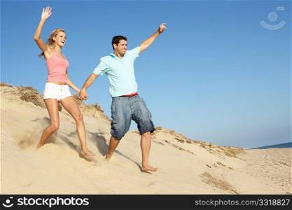 Couple Enjoying Beach Holiday Running Down Dune