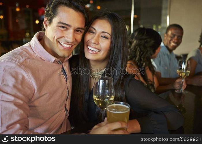 Couple Enjoying Drink At Bar With Friends
