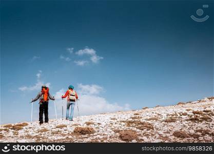 Couple enjoying hiking in wintertime. The desire for heights and extremes, what inspired these brave tourists to the highest mountains.. Active Couple Walking with Sticks in the Mountains
