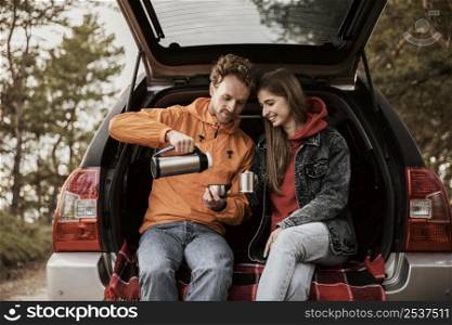 couple enjoying hot beverage while road trip