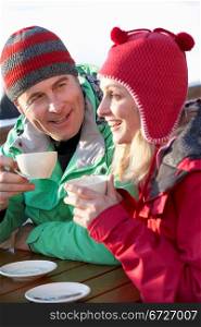 Couple Enjoying Hot Drink In Cafe At Ski Resort