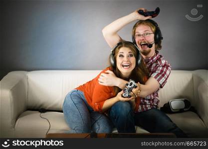 Couple enjoying leisure time by playing video games together, man and woman being emotional by game.. Gamer couple playing games