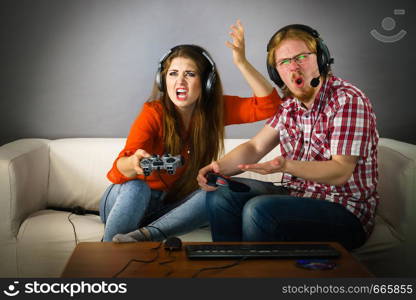 Couple enjoying leisure time by playing video games together, man and woman being shocked by game.. Gaming couple playing games